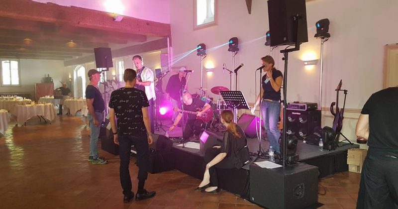 Scène de concert au Domaine de Grand Maison avec musiciens, matériel de sono et éclairage en préparation.