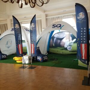 Stand d'exposition pour la Ryder Cup avec tentes, drapeaux et décor de golf.