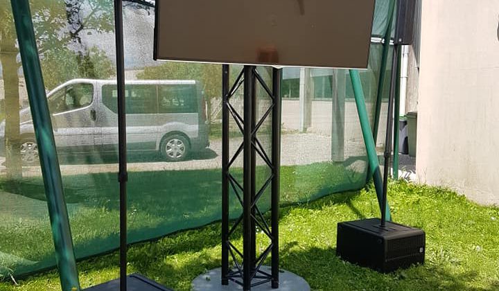 Écran monté sur un support avec enceintes, pour la retransmission de la finale de Roland-Garros en extérieur.