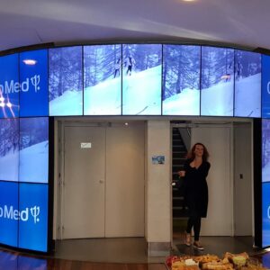 Hall d'accueil du siège social du Club Med avec un écran vidéo montrant des paysages enneigés et des visiteurs.