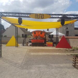 Installation scénique colorée pour un festival techno à Villiers-le-Mahieu, avec une scène et des éléments décoratifs.