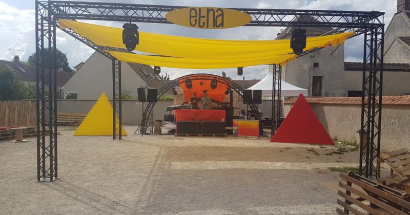 Installation scénique colorée pour un festival techno à Villiers-le-Mahieu, avec une scène et des éléments décoratifs.