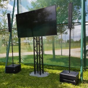 Écran de télévision monté sur trépied, entouré de deux haut-parleurs, en extérieur lors de la retransmission de Roland Garros 2019.