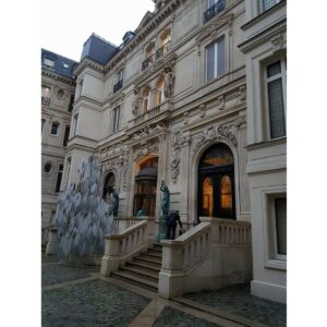 Entrée de la Gallerie Gaggeneau, avec des sculptures, des escaliers et un décor architectural élaboré.