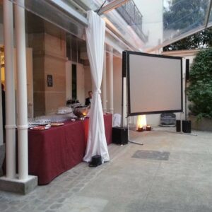 Espace de restauration avec buffet, écran de projection et matériel de son dans un cadre élégant.