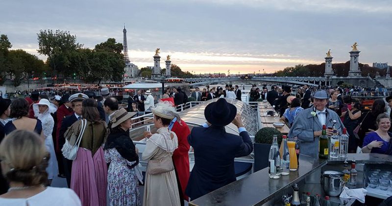 Concert philharmonique sur une péniche à Paris, ambiance festive avec des invités en costume d'époque.