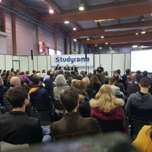 Public présent lors de l'événement Studyrama, avec des intervenants sur scène et un écran de présentation.