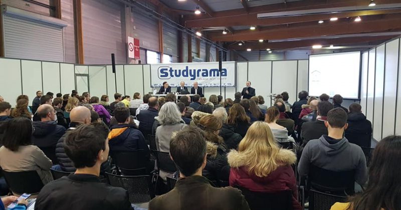 Public présent lors de l'événement Studyrama, avec des intervenants sur scène et un écran de présentation.