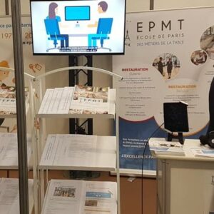 Stand d'exposition de l'École de Paris des Métiers de la Table avec un écran et des brochures sur la restauration.