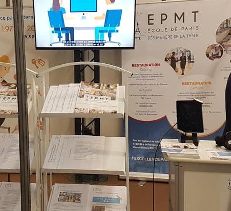 Stand d'exposition de l'École de Paris des Métiers de la Table avec un écran et des brochures sur la restauration.