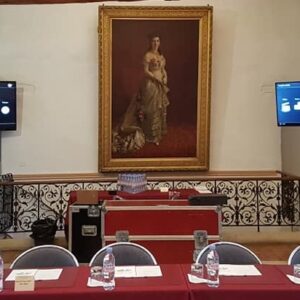 Installation de quatre écrans sur totem pour un événement, avec une table et des chaises dans un cadre décoratif.