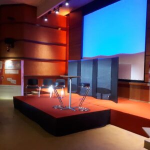 Scène de théâtre avec éclairage, sièges et écran. Installation fixe par Symbiose Organisation pour événement.
