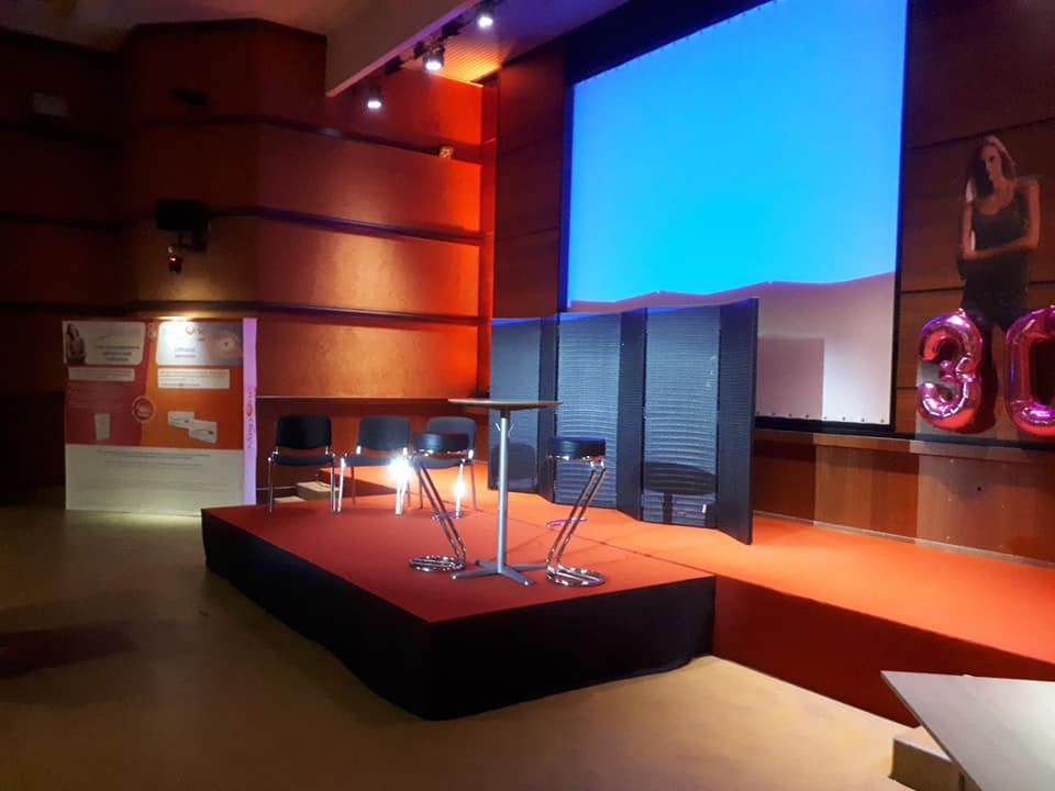 Scène de théâtre avec éclairage, sièges et écran. Installation fixe par Symbiose Organisation pour événement.