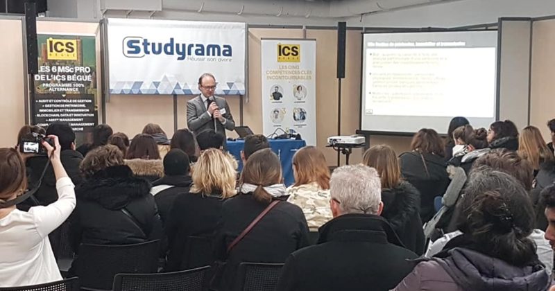 Conférence au salon d'expo Espace Champerret, avec un intervenant devant un public attentif et des présentations en arrière-plan.