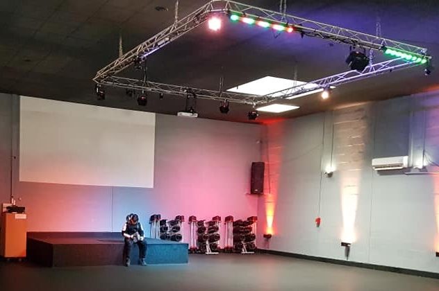 Salle de spectacle avec éclairage multicolore et équipements audio, préparée pour un événement.