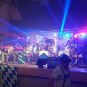Concert avec des musiciens en tenue traditionnelle, éclairage coloré et équipements de sono sur scène.