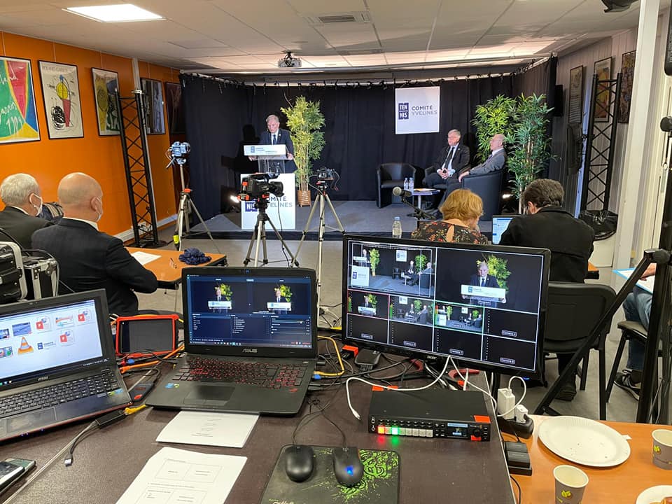 Assemblée générale avec présentation en direct, technologie de streaming et équipement audiovisuel. Participants attentifs.