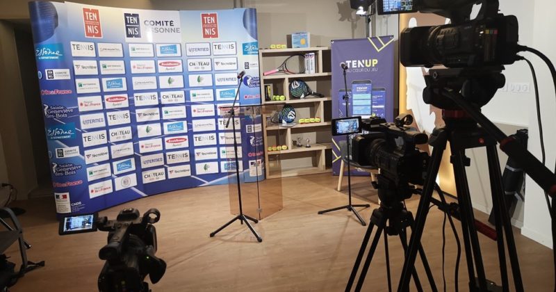 Caméras prêtes pour un événement de tennis, avec toile de fond et matériel de présentation en vue.