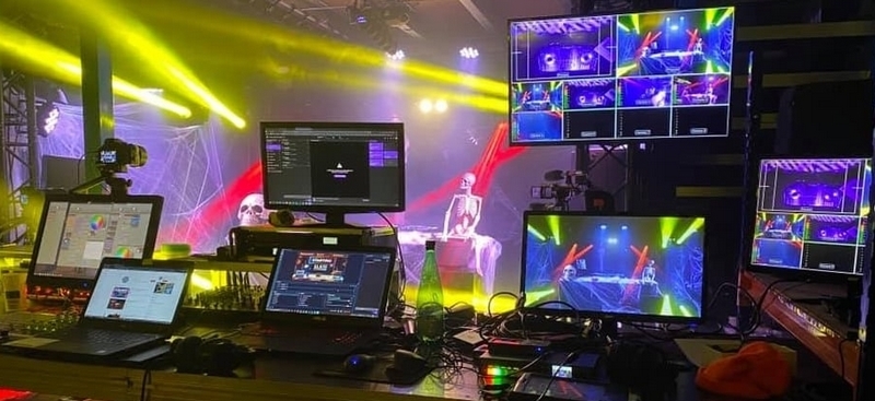 Poste de contrôle pour son et éclairage avec plusieurs écrans et équipements, illuminé par des lumières colorées.