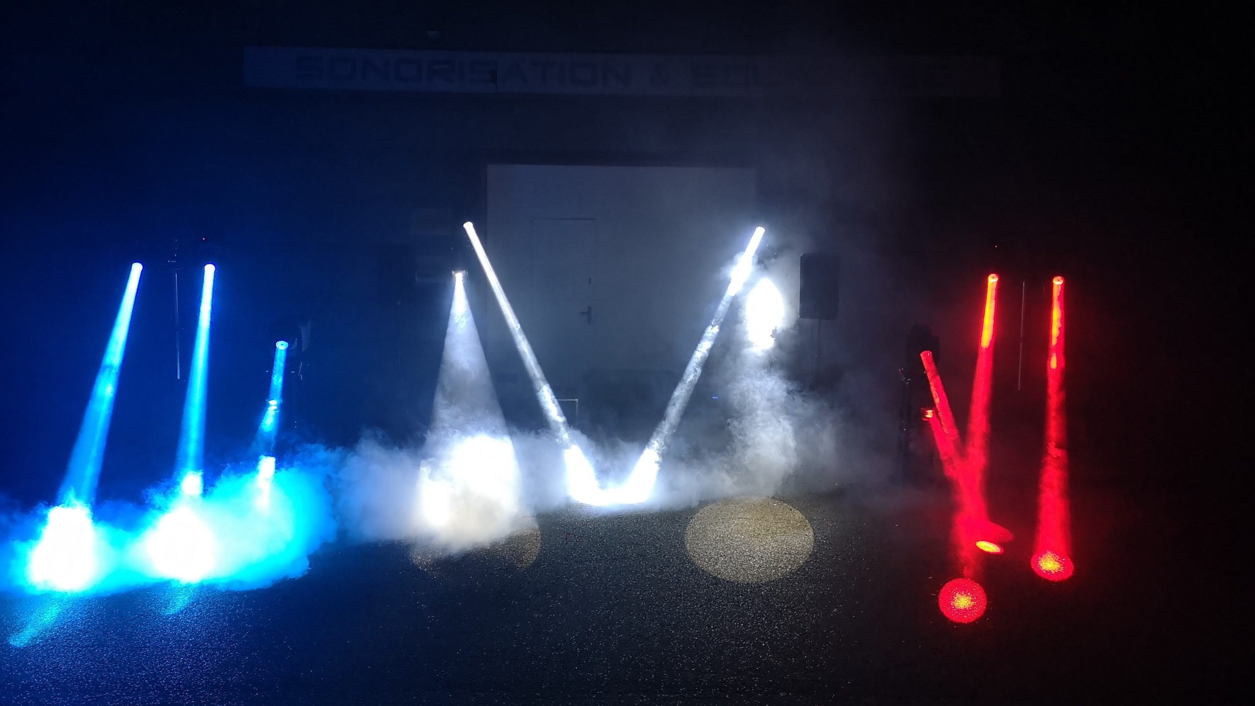 Light show en hommage au personnel médical, avec des faisceaux lumineux bleus et rouges dans une ambiance brumeuse.