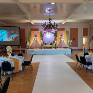 Décor coloré d'un mariage indien à la salle Saint-Exupéry, avec scène, tables et projecteur le 3 juillet 2021.
