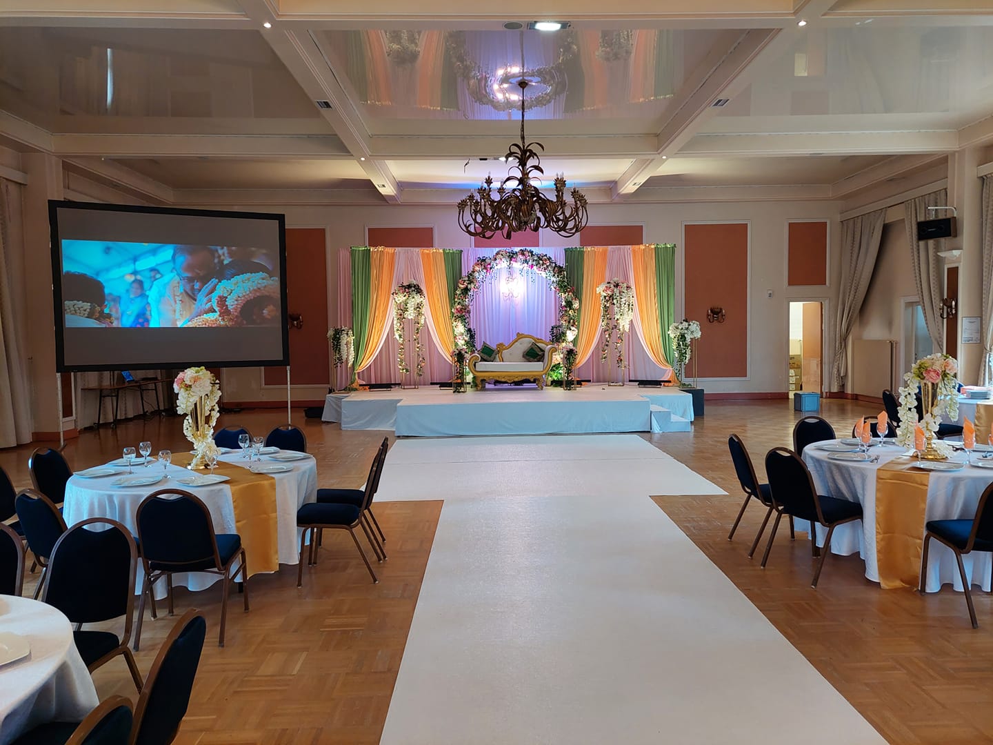 Décor coloré d'un mariage indien à la salle Saint-Exupéry, avec scène, tables et projecteur le 3 juillet 2021.