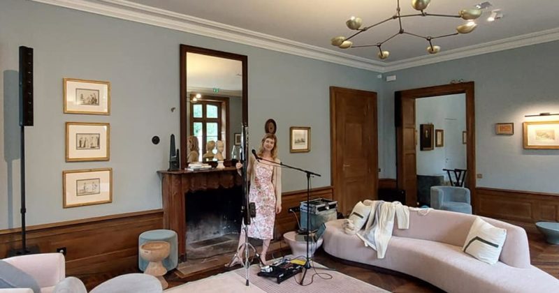 Naomi Greene dans un salon au Château de Primard, préparant un événement avec du matériel de sonorisation et d'éclairage.