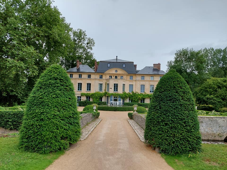 Vue du Château de Primard, où se déroule un événement audio pour Naomi Greene, entouré de verdure.