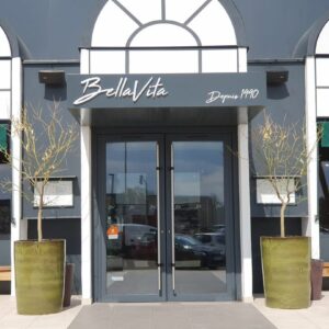 Entrée du restaurant BellaVita à Coignières, avec des pots de fleurs et une enseigne élégante.