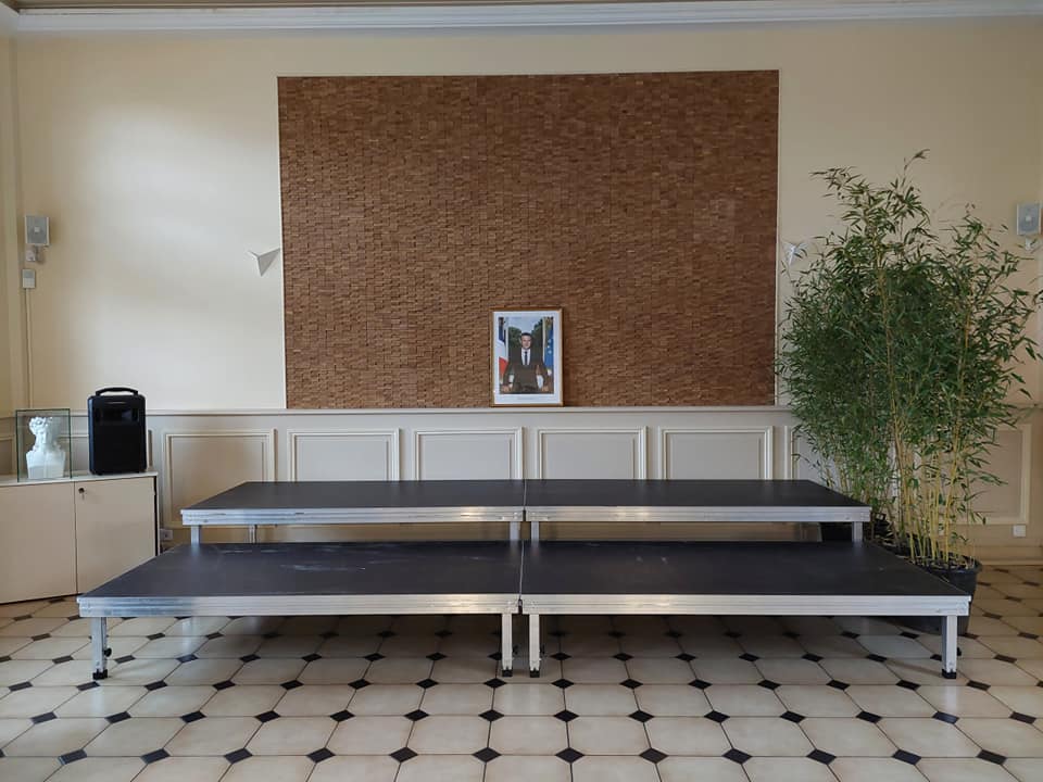 Scène montée pour le conseil municipal de Coignières, avec fond en osier et plantes, photographiée le 22 octobre 2021.