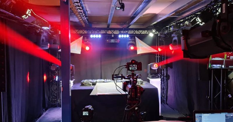 Studio de live streaming avec matériel de son et éclairage, ambiance lumineuse et caméras prêtes pour l'événement.