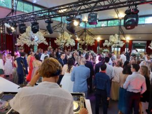 Foule en fête lors d'un mariage au domaine du moulin des marais, avec DJ et éclairage élégant.