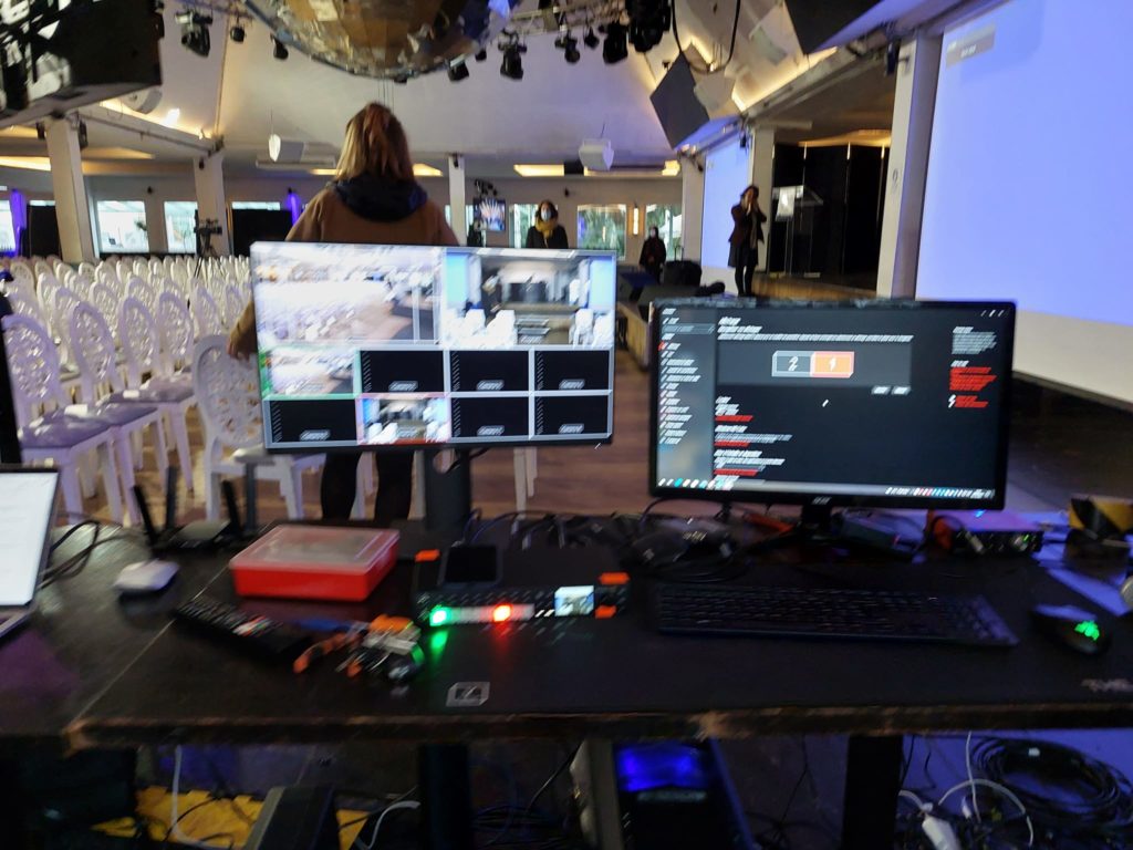 Poste de travail pour captation vidéo et son lors d'un événement le 7 décembre 2021, avec plusieurs écrans et équipements de diffusion.