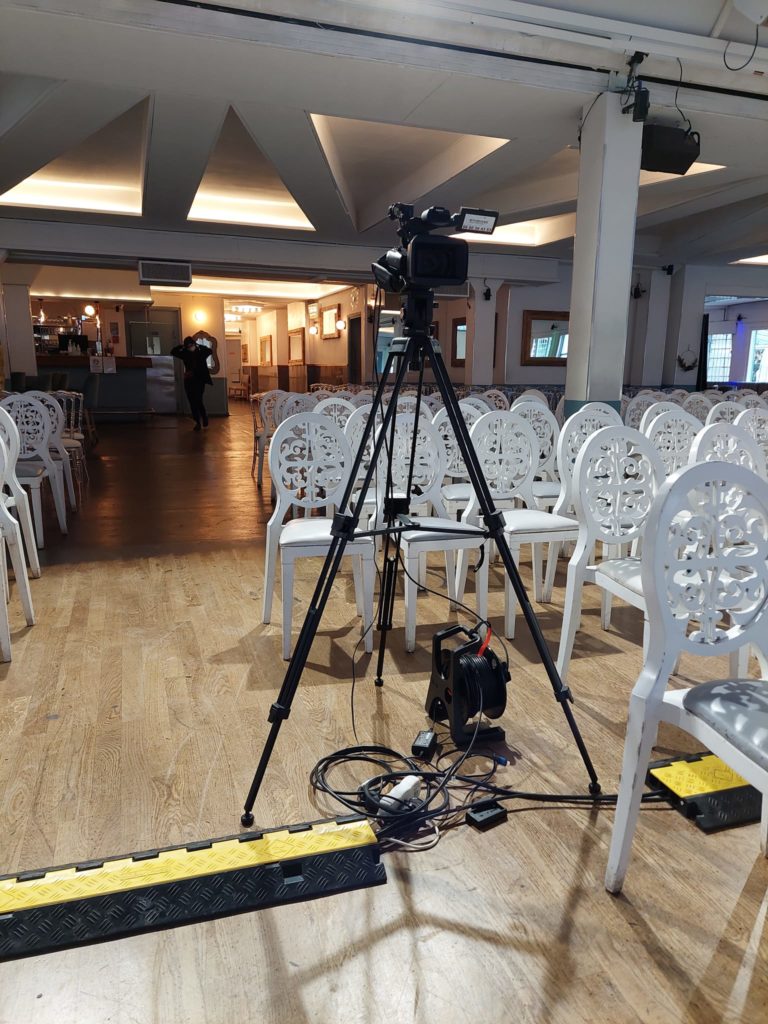 Caméra sur trépied pour captation vidéo avec son, configurée pour un événement le 7 décembre 2021 dans une salle.