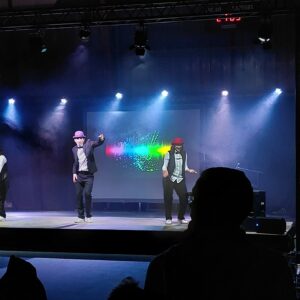 Danseurs en costume sur scène lors du Téléthon de Villepreux, éclairage coloré en arrière-plan.