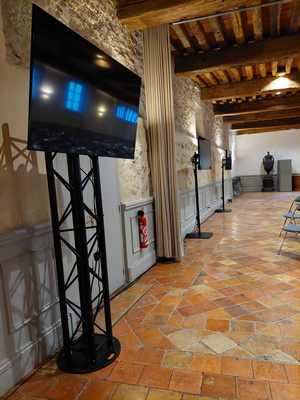 Installation de matériel audiovisuel dans un hall, avec des écrans montés sur trépieds.