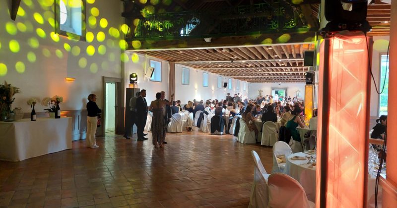Salle de réception animée pour un mariage au Domaine de Grand-Maison, avec éclairage coloré et invités.