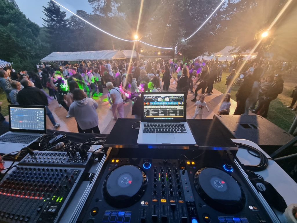 Foule festive dans un parc, éclairage coloré et matériel de DJ en avant-plan pour la fête à Bougival.
