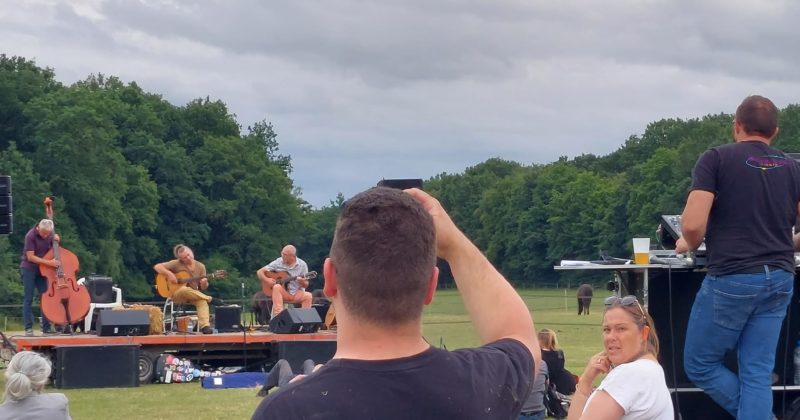 Concert de jazz en plein air, ambiance détendue, avec des musiciens sur scène et des spectateurs profitant du moment.