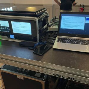 Installation technique avec matériel de sonorisation et un ordinateur portable dans un cadre professionnel.