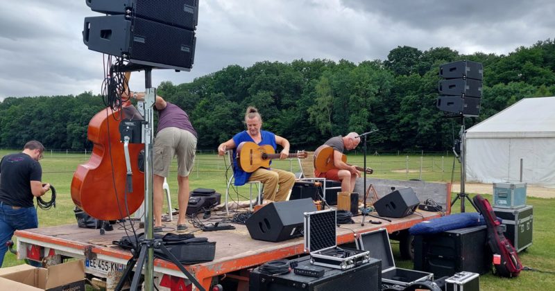 Préparatifs d'un concert champêtre avec musiciens sur scène, sonorisation et équipements en attente d'utilisation. Haras de la Cense, 2022.