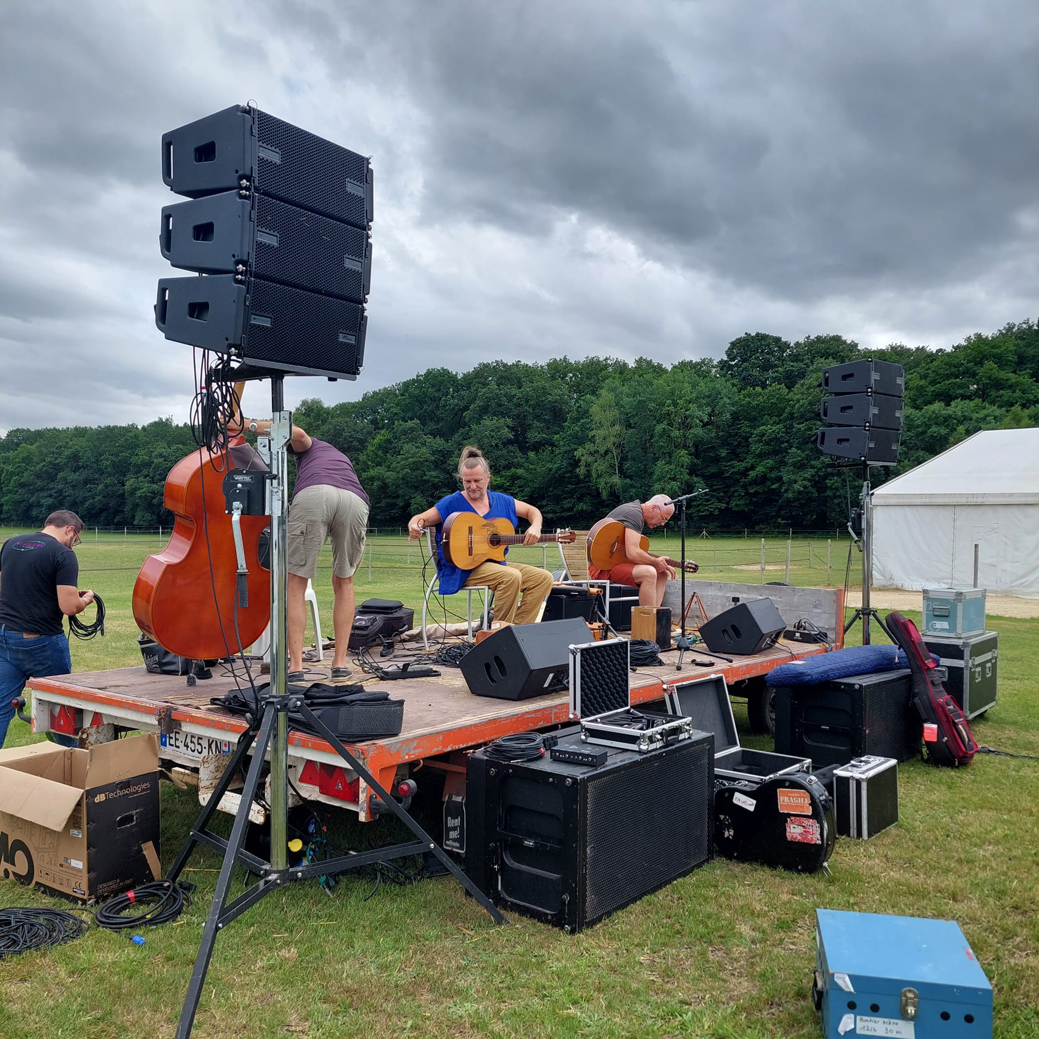 Préparatifs d'un concert champêtre avec musiciens sur scène, sonorisation et équipements en attente d'utilisation. Haras de la Cense, 2022.