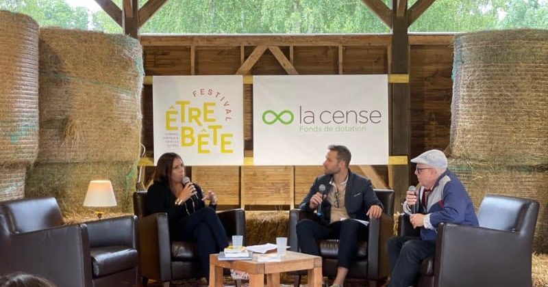 Conférence au Haras de la Cense avec des intervenants assis sur des fauteuils, devant des banderoles de l'événement et de l'organisation.