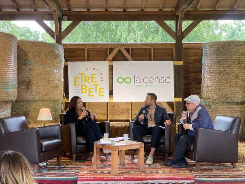 Conférence au Haras de la Cense avec des intervenants assis sur des fauteuils, devant des banderoles de l'événement et de l'organisation.