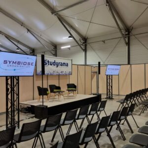 Stand de Studyrama avec écrans Sony Bravia de 55 pouces, logo Symbiose Organisation et chaises disposées pour un événement.