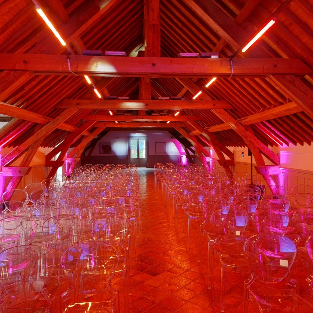Salle décorée avec des lumières roses et un agencement de chaises transparentes pour l'événement Crédit Agricole du 23 septembre.