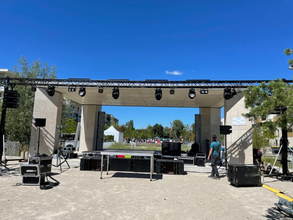 Installation d'une scène pour un événement à Saint-Cyr-l'École le 2 juillet 2022, avec équipement de son et éclairage.