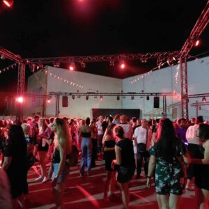 Foule animée lors du Bal des Pompiers de Poissy 2022, avec des jeux de lumière et une ambiance festive.