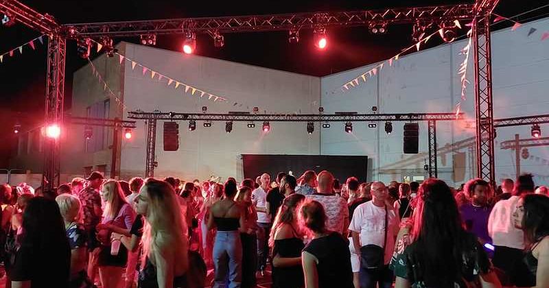 Foule animée lors du Bal des Pompiers de Poissy 2022, avec des jeux de lumière et une ambiance festive.