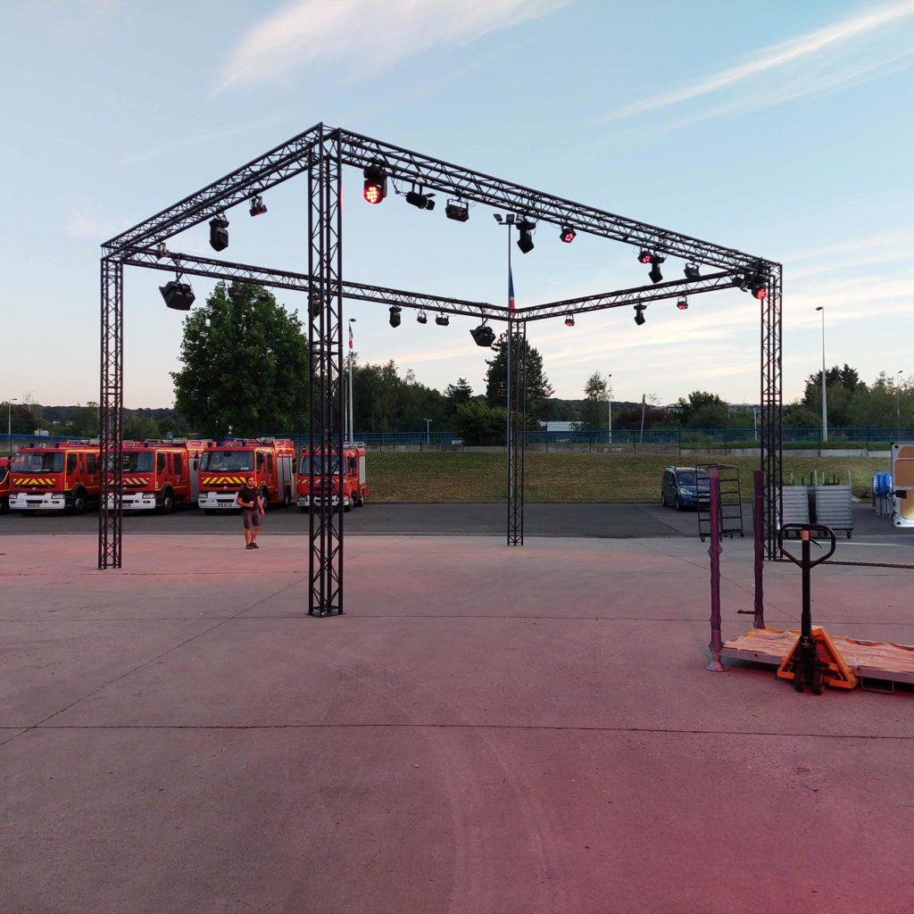 Scène avec éclairage pour le Bal des Pompiers de Poissy, avec des voitures de pompier en arrière-plan.
